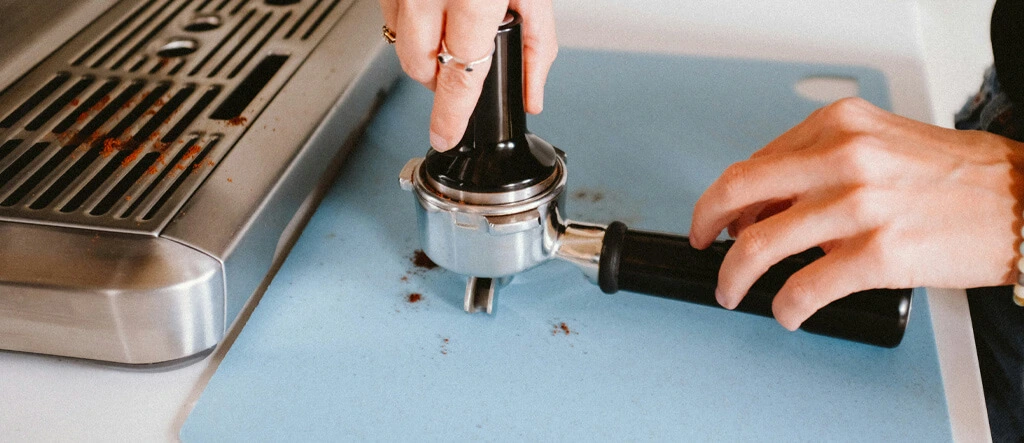 Close-up of espresso tamper evenly distributing coffee grounds