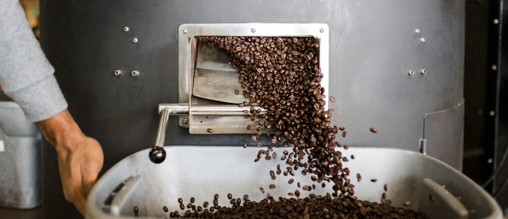 Freshly roasted coffee beans emerging from a roaster, highlighting a key step in coffee preparation.