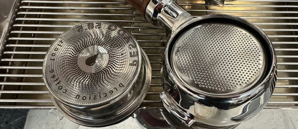 Close-up of an empty espresso machine coffee basket, showcasing its fine holes for water flow during espresso extraction.
