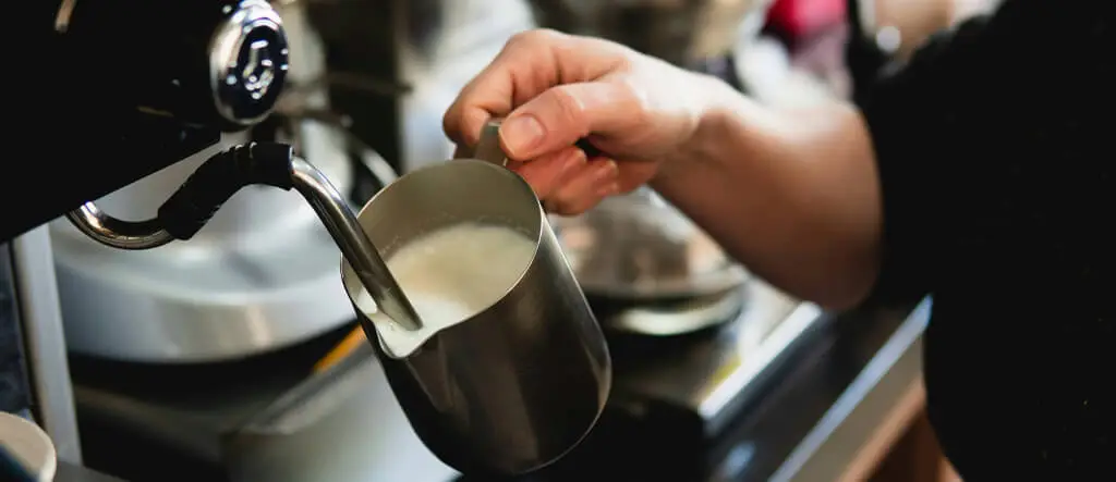 Barista frothing milk with a steam wand on an espresso machine