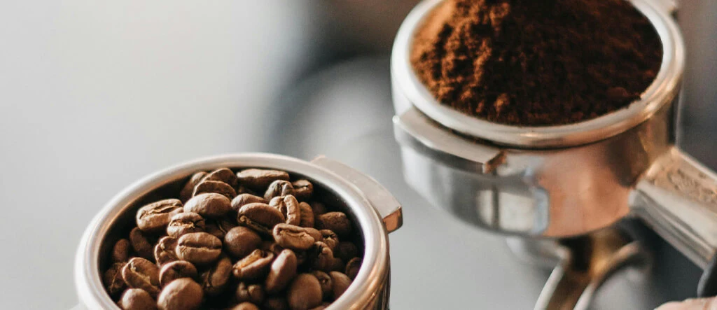 A side-by-side comparison of whole coffee beans and finely ground espresso beans, illustrating the differences between them.