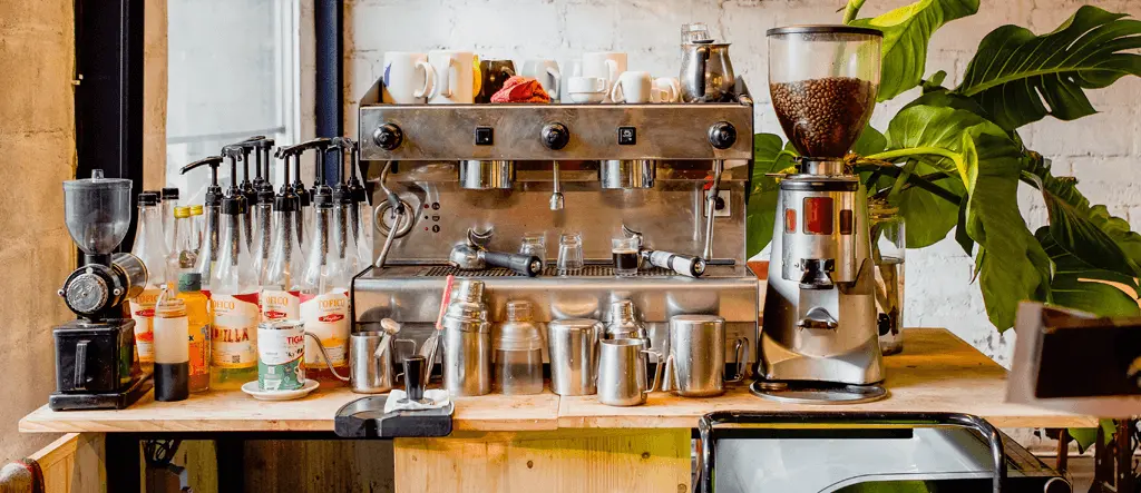 A modern home barista setup with a coffee machine, grinder, and accessories on a stylish countertop.