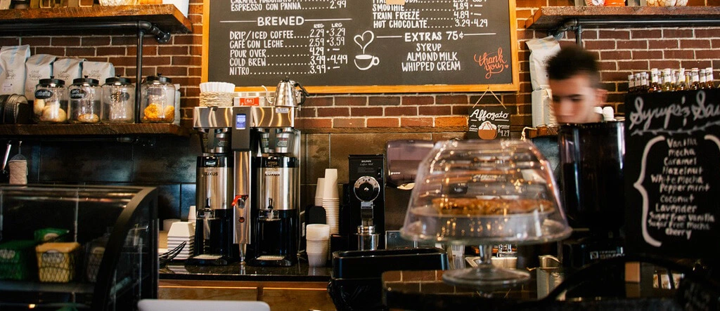 A barista in a cafe surrounded by coffee equipment, including a coffee  espresso machine, and other home barista accessories