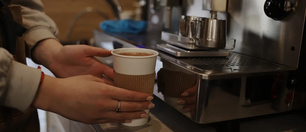 A barista brewing coffee using high-quality home barista accessories, including a grinder and tamper.