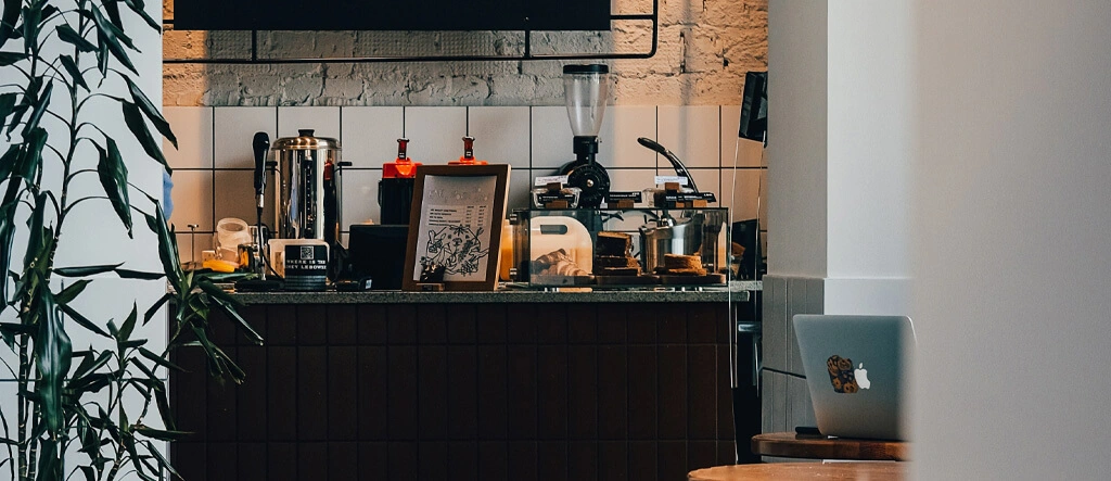 A well-organized home coffee bar with a coffee maker, mugs, storage jars, and decorative accents on a stylish countertop.