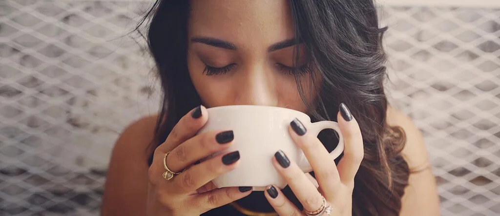 A woman sipping coffee from a cup and enjoying the moment