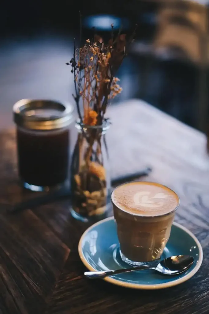 A single latte on a table accompanied by fresh flowers, creating a serene and elegant scene