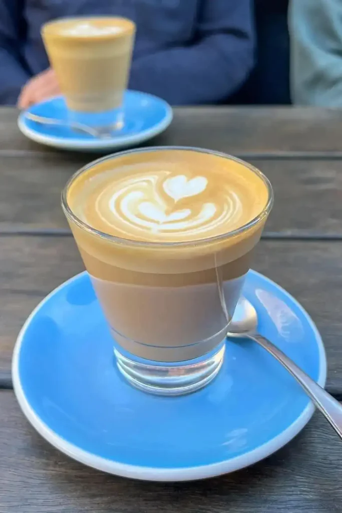 Two lattes served on a wooden table in a cozy café setting