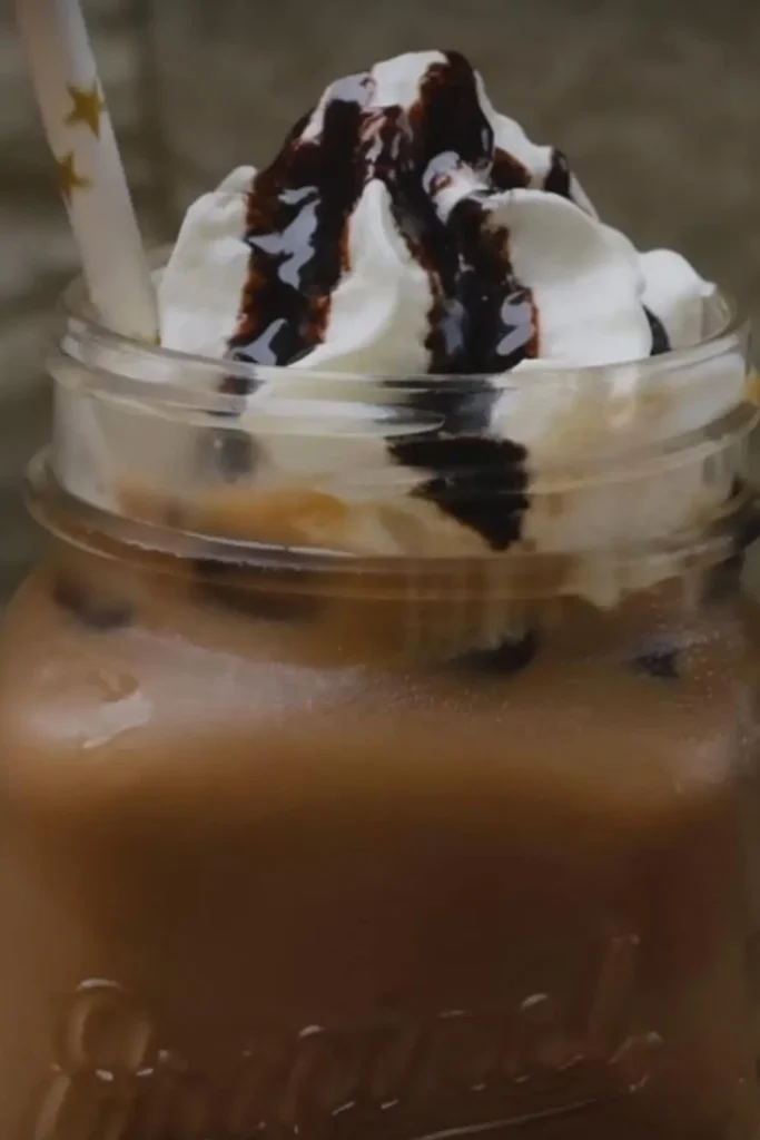 Top half of a Caffè Mocha served in a mason jar, topped with whipped cream and drizzled with chocolate syrup.