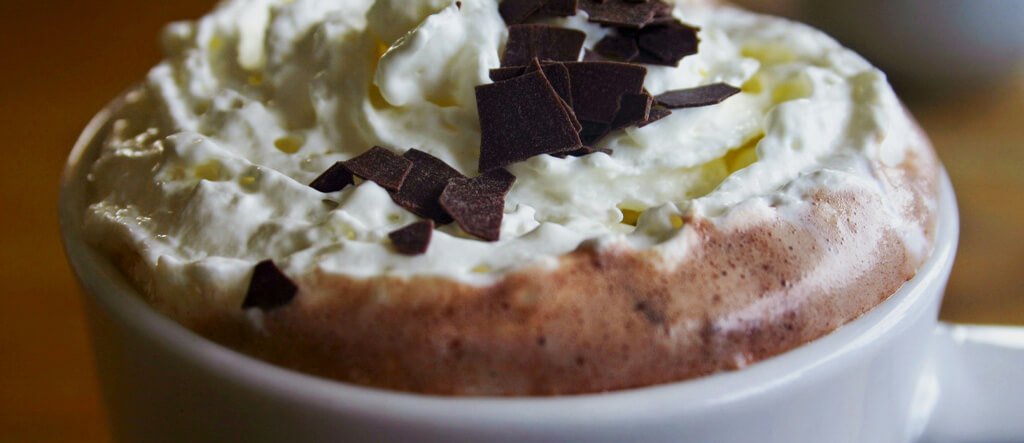 Top view of a Caffè Mocha with whipped cream and chocolate flakes, showcasing its rich and creamy texture.