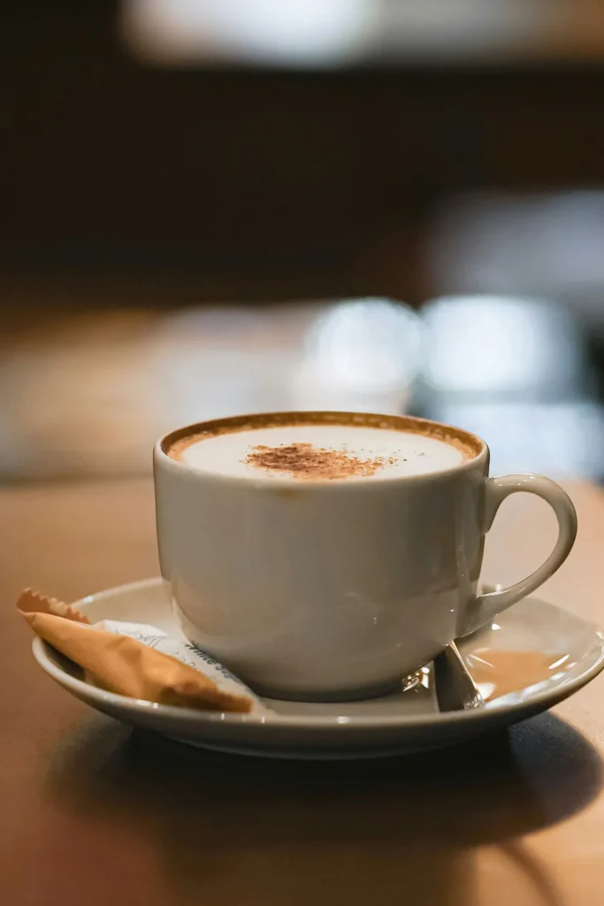 A warm cappuccino in a ceramic cup placed on a wooden bench.