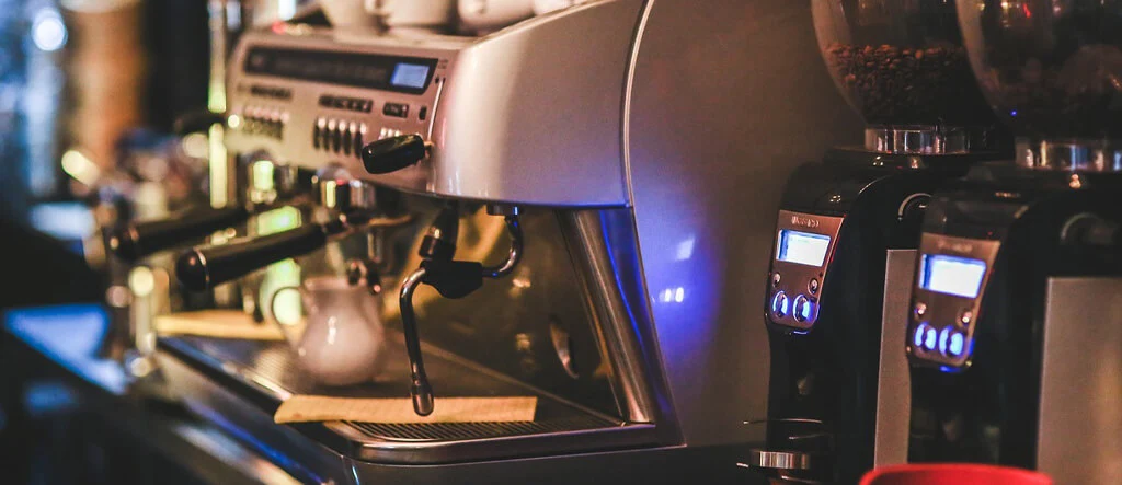 Close-up view of an espresso machine highlighting its portafilter, steam wand, and control panel.