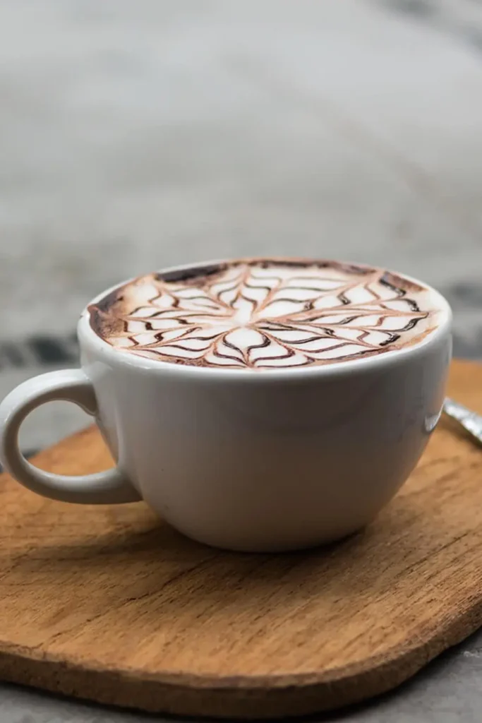 A cup of cappuccino with a frothy milk foam layer, served in a white mug.