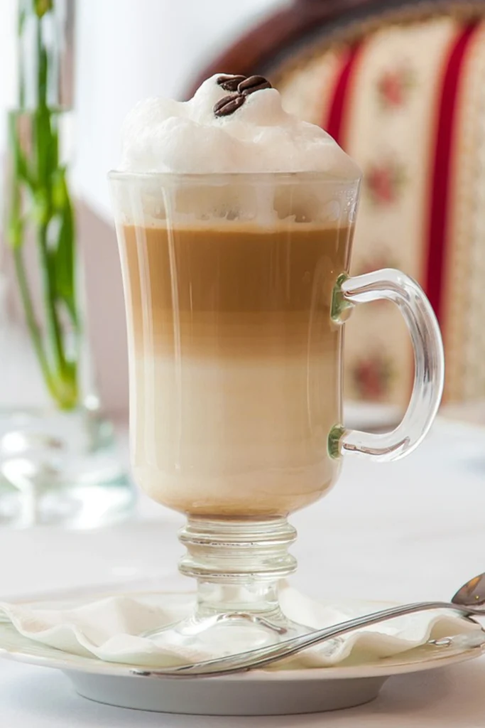 A beautifully layered Macchiato in a glass cup, showcasing rich espresso topped with a dollop of frothy milk.