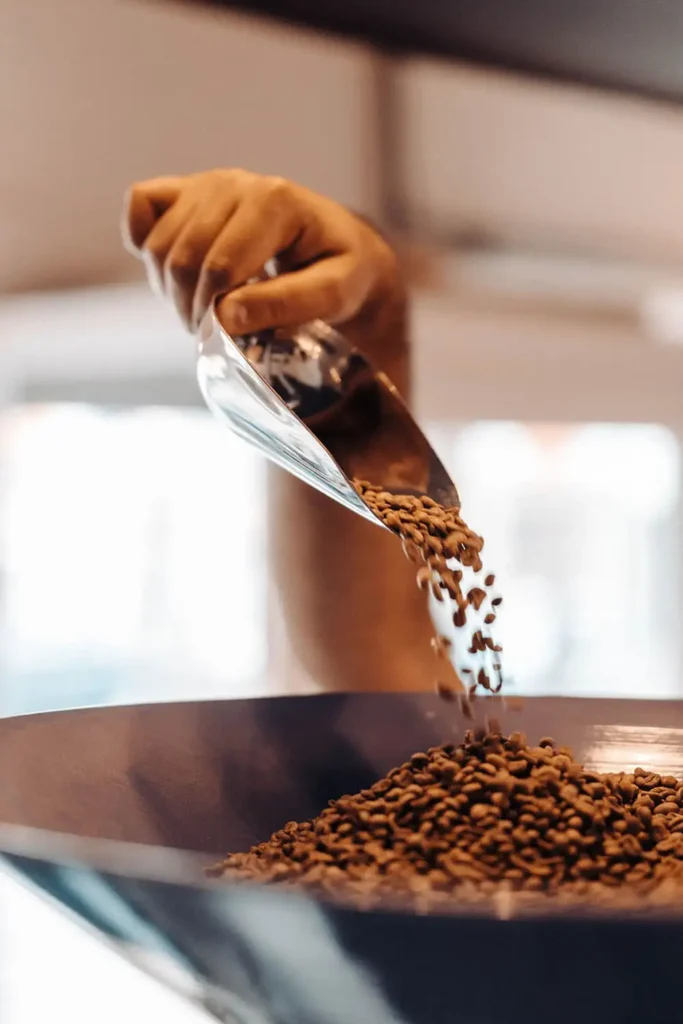 Close-up of a person scoopong coffee beans into a hopper, preparing for grinding and brewing a fresh cup of coffee.