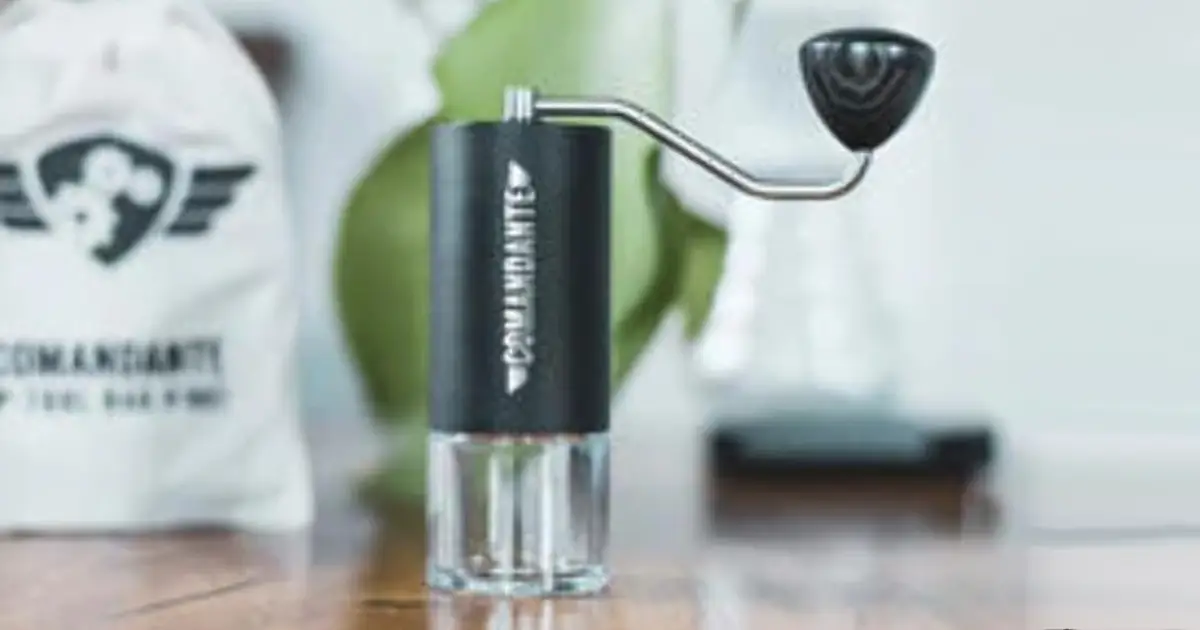 Comandante Grinder Review: Is This Premium Hand Grinder Worth It? 2 A close-up of a Comandante C40 grinder beside freshly roasted beans, a V60 dripper, and a cup of pour-over coffee on a wooden bench.