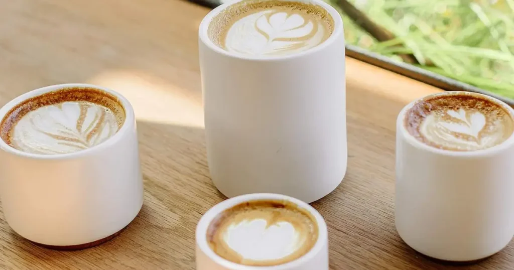 Fellow Monty Cups Review 46 Fellow Monty Cups in matte white with a copper base, perfect for latte art and heat retention, displayed stylishly in a coffee setup.