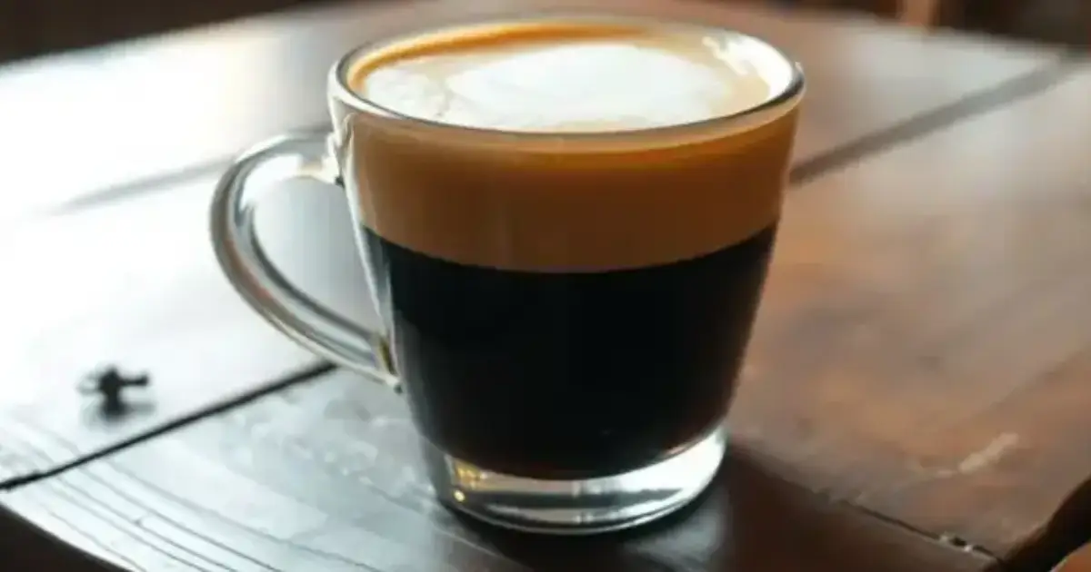 Macchiato - For Strong Coffee Lovers 2 A freshly made espresso macchiato in a clear glass cup on a wooden café table.