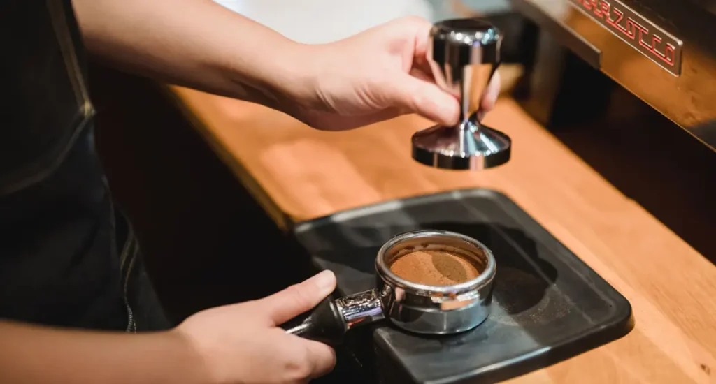 7 Best Espresso Tampers for Perfect Coffee at Home (2026 Review) 203 Barista tamping espresso grounds with a precision tamper in a portafilter