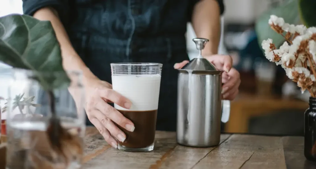 ☕ Elevate Your Coffee Game - Best Milk Frothers of 2026 9 Barista showing milk froth on coffee using one of the best milk frothers