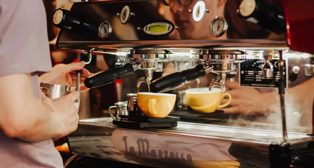 Best Premium Espresso Machines for Home Baristas 8 Barista beside a high-end espresso machine, representing premium home coffee setups.