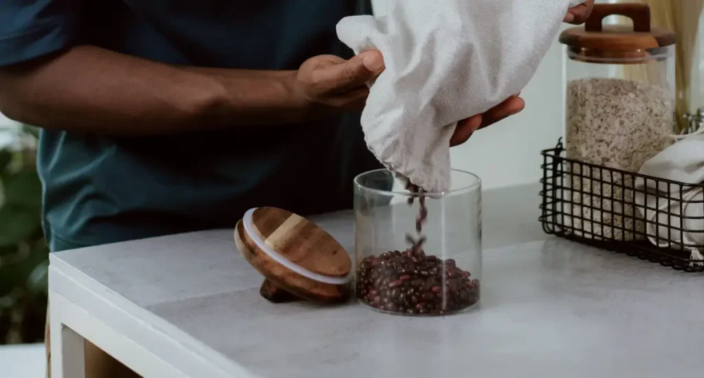Is Your Coffee Canister Ruining Your Beans? Our Top Picks 95 Man pouring coffee beans into a coffee canister to preserve the freshness of the beans