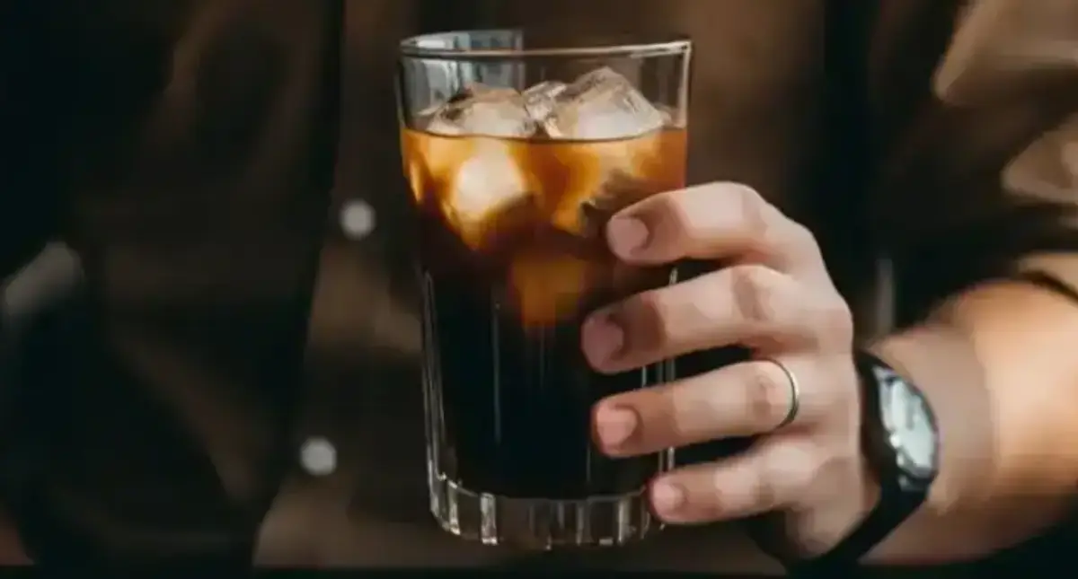 Cold Brew Espresso - What It Is & How to Make It ❄️ 2 Man holding a glass of cold brew espresso, showcasing its dark, refreshing appearance.