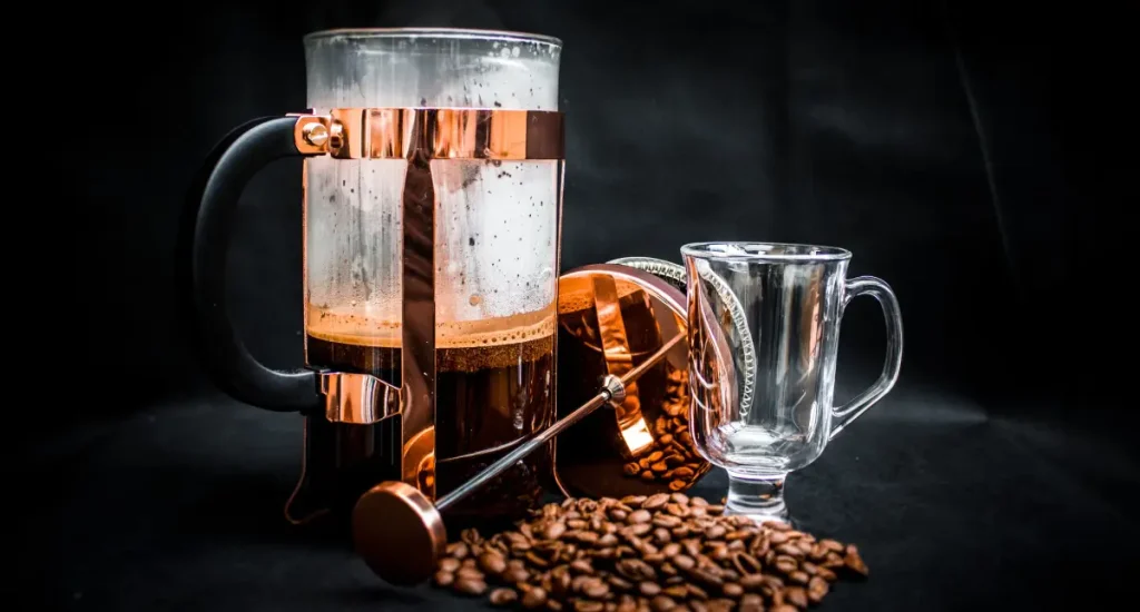 Espresso vs French Press vs Pour Over: Which Brewing Method Makes the Best Coffee? 4 A French press filled with freshly brewed coffee with coffee beans and glass