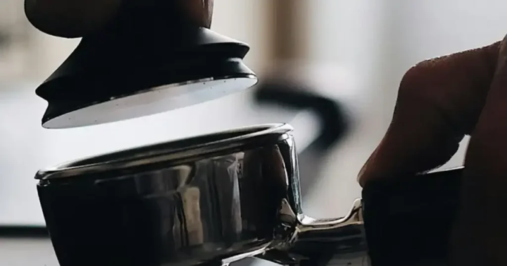 LuxHaus Tamper Review – A Solid Pick for Beginner Baristas 27 Barista tamping espresso grounds with a precision tamper in a portafilter