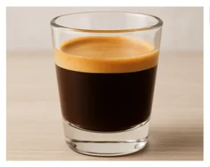 Triple Shot of Espresso Triple shot of espresso in a clear glass with golden crema on a wooden surface