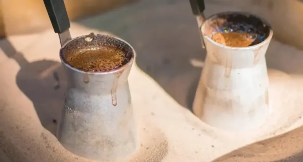 Espresso vs Turkish vs Drip Coffee: Which Is Best? 5 Two traditional cups of Turkish coffee with foam and copper coffee pots in sand