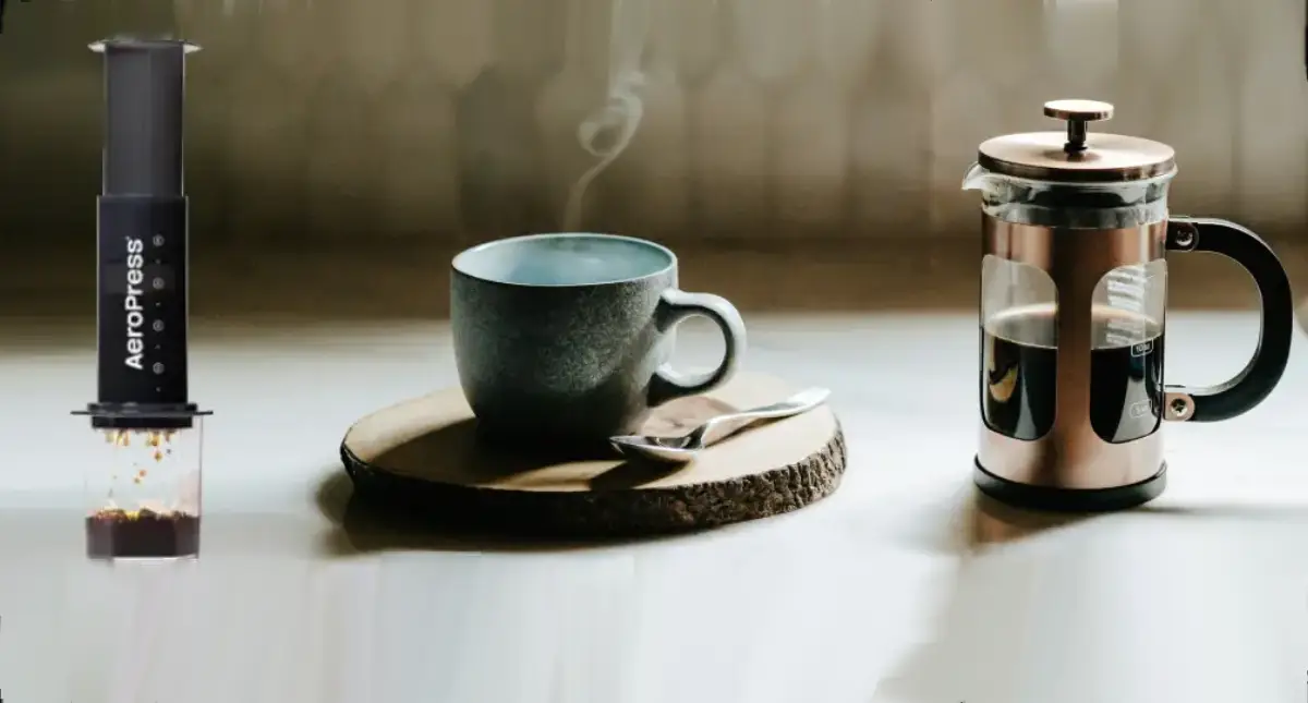AeroPress vs French Press: Which Is Better for Your Brew Style? ☕ 2 French Press and AeroPress side by side on a bench with a cup of coffee