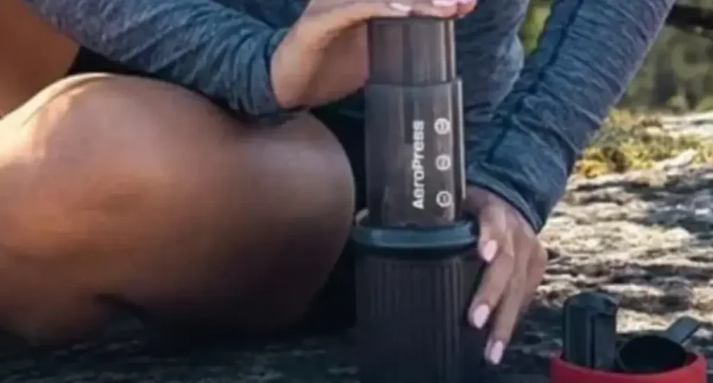 Woman Using A Aeropress Woman brewing coffee outdoors using the AeroPress Go