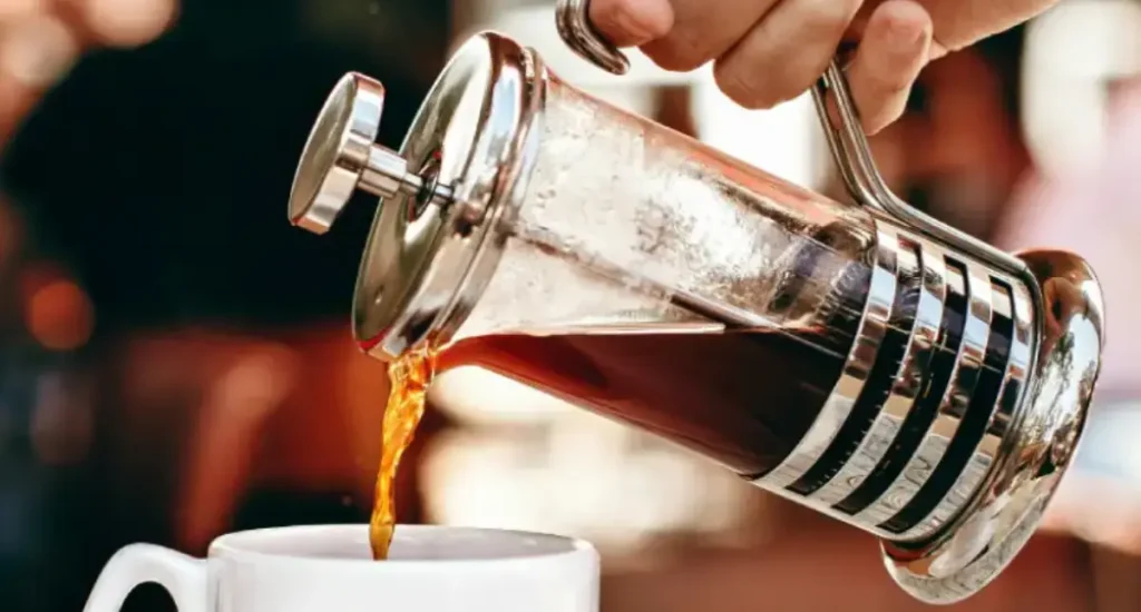 Best French Press Coffee Makers for Rich, Full-Bodied Brews 🫖 198 Person pouring freshly brewed coffee from a French press into a ceramic cup
