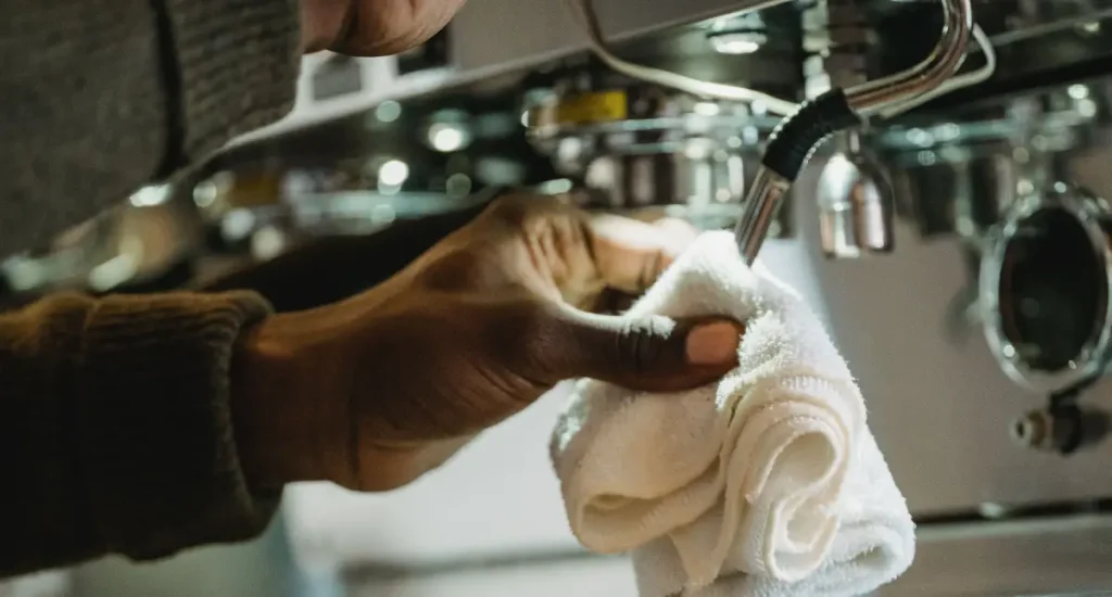 ☕ Espresso Machine Maintenance Tips for Boiler Types 196 Barista cleaning the steam wand of an espresso machine with a cloth