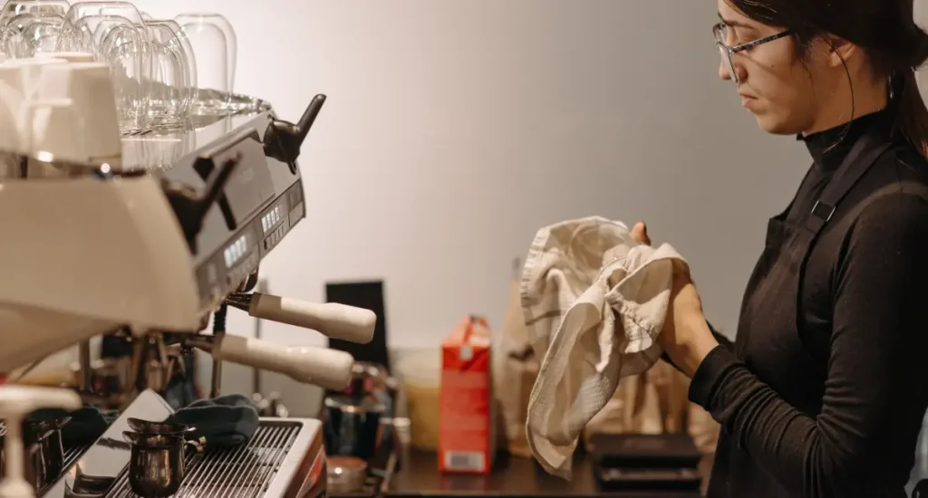 ☕ Espresso Machine Maintenance Tips for Boiler Types 4 Barista performing regular Espresso Machine Maintenance with a cloth at a café