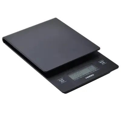 Hario V60 Drip Coffee Scale with Timer Hario V60 coffee scale with timer next to a glass carafe and dripper