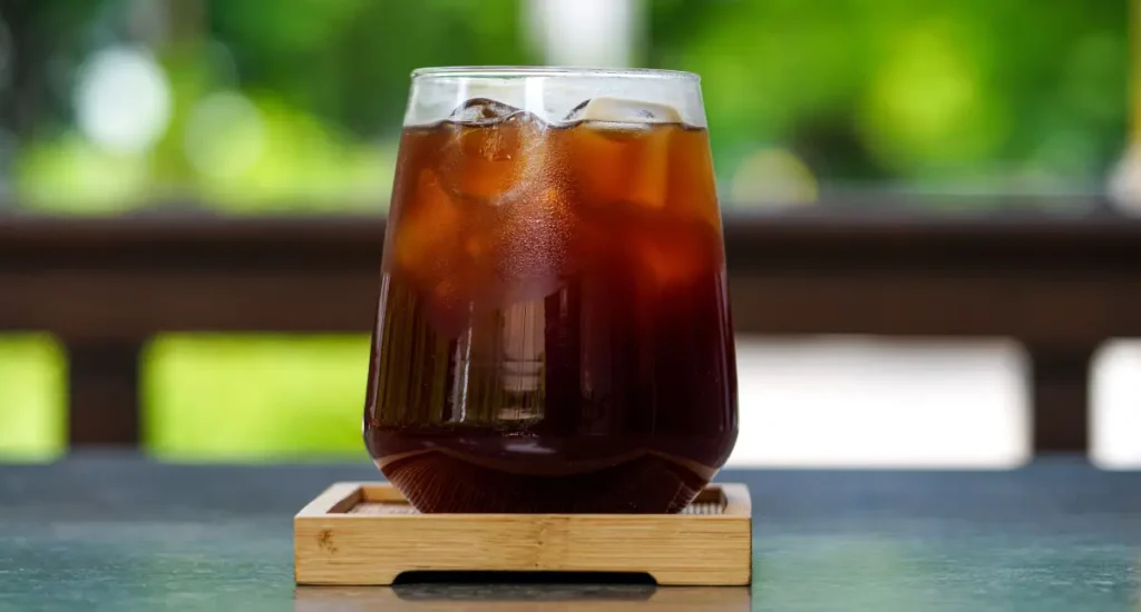 How to Make Cold Brew in a French Press ☕ 83 Glass of cold brew coffee on a wooden bench in natural light