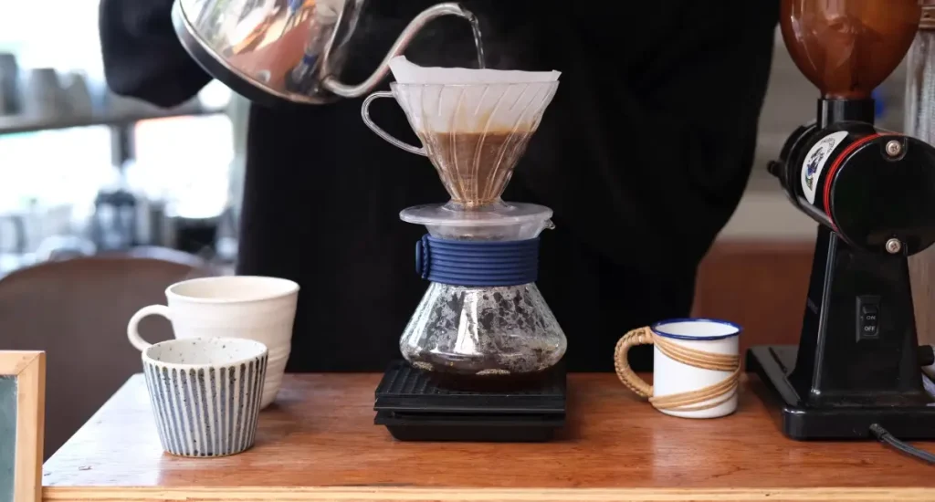 How to Make Pour Over Coffee Like a Barista ☕ 79 Person pouring hot water into a pour over coffee dripper with a gooseneck kettle