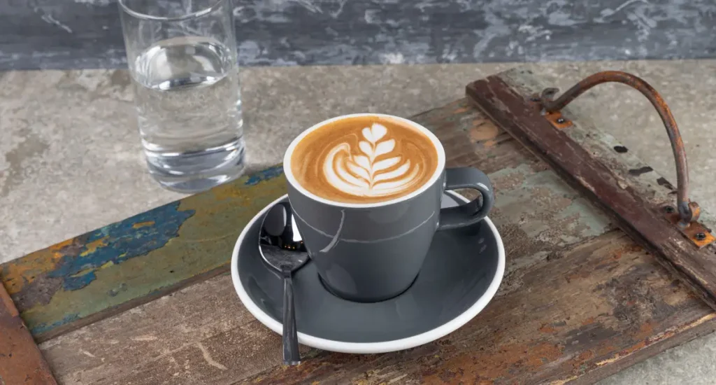 What Is a Flat White? Your Guide to This Smooth, Strong Espresso Classic ☕ 90 Flat white coffee on a wooden tray with glass of water behind
