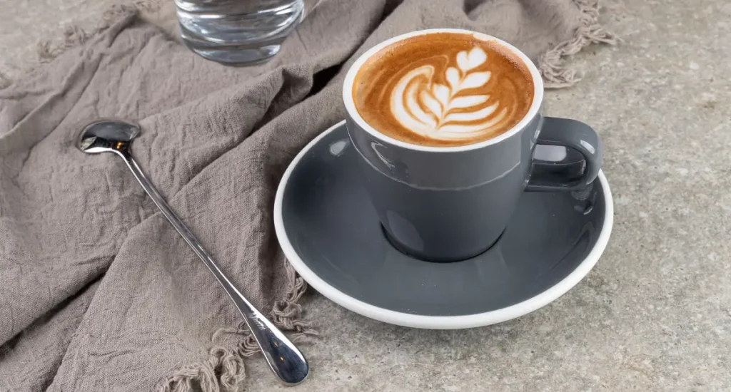 What Is a Flat White? Your Guide to This Smooth, Strong Espresso Classic ☕ 3 A flat white in a ceramic cup with rich and velvety microfoam and a rosetta latte art.
