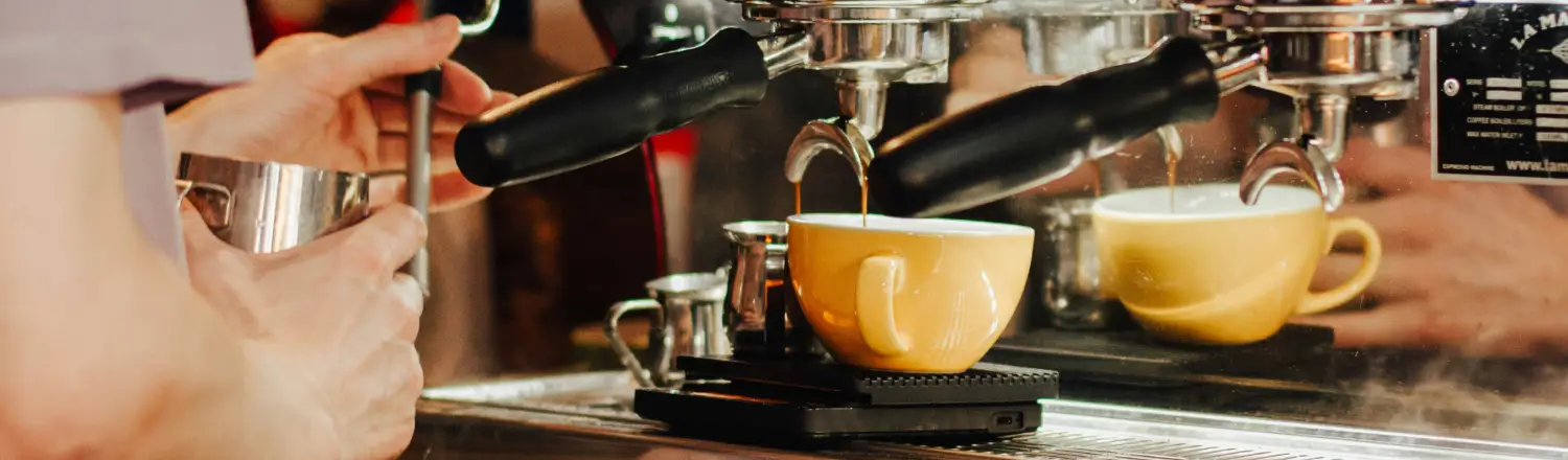 Latte vs Cappuccino: What’s the Difference? ☕ 2 Barista steaming milk and making a cappuccino using an espresso machine