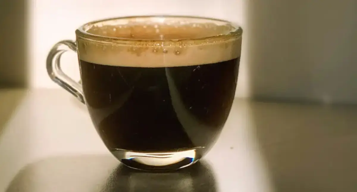 What Is a Lungo? (Italian-Style Long Espresso Explained) ๐ฎ๐น 2 Wonder what is a lungo - It's A freshly brewed lungo in a small glass cup sitting on a wooden table