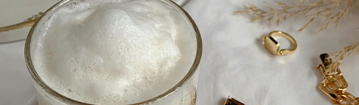 How to Get the Perfect Kaimaki (Foam) Every Time ☕✨ 2 A cup of coffee topped with white foam sitting on a table in a warm, inviting setting.