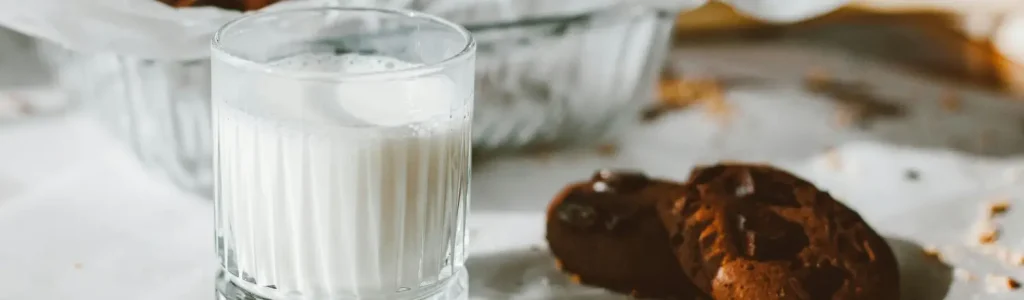 🌰 Oat Milk vs Almond Milk: Which Froths Better? 78 Glass of milk beside two cookies on a table with a blurred background