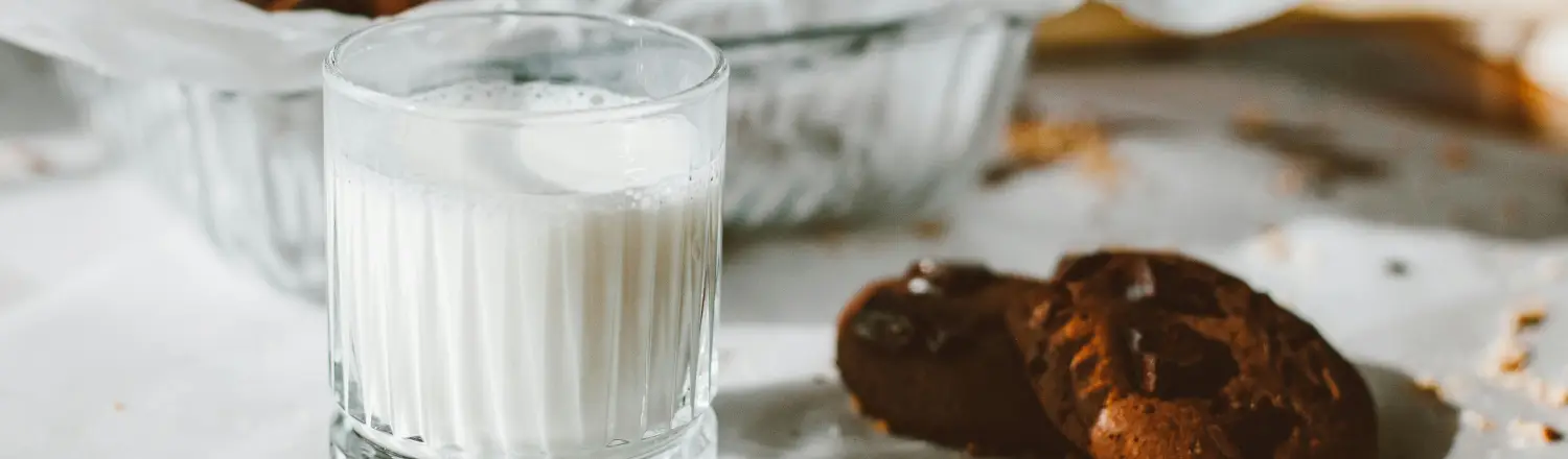 🌰 Oat Milk vs Almond Milk: Which Froths Better? 2 Glass of milk beside two cookies on a table with a blurred background