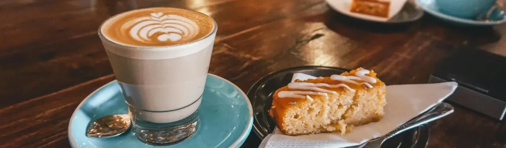 Chai Latte vs Dirty Chai: What’s the Difference & Which Should You Try? 70 Glass of creamy chai latte on a café table beside a slice of cake
