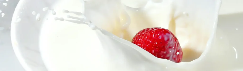 🌱 Top 5 Plant-Based Milks for Frothy Lattes (That Actually Foam Like Dairy!) 76 Fresh strawberry splashing into a bowl of milk, creating a creamy swirl and droplets.