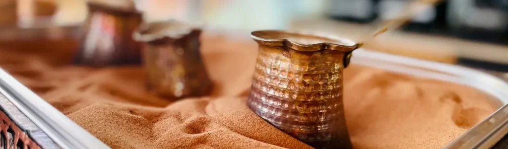 How to Make Turkish Coffee at Home (Step-by-Step Guide ☕✨) 38 Three cezves brewing Turkish coffee in hot sand using the traditional method
