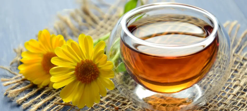 🌙 10 Best Herbal Teas for Relaxation & Sleep (Naturally Soothe Your Mind & Body) 60 Glass of herbal tea for relaxation and sleep with two yellow daffodils beside it
